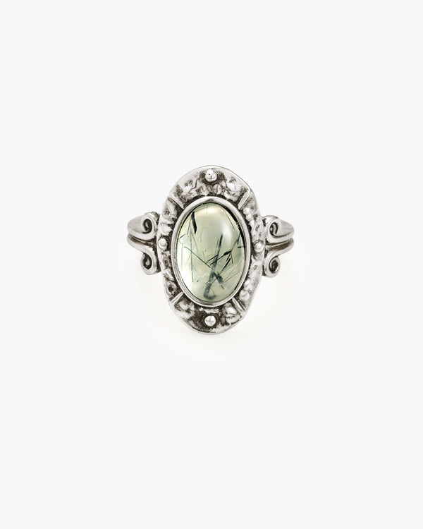 Oval prehnite stone ring with intricate silver-plated brass setting and swirling band details.