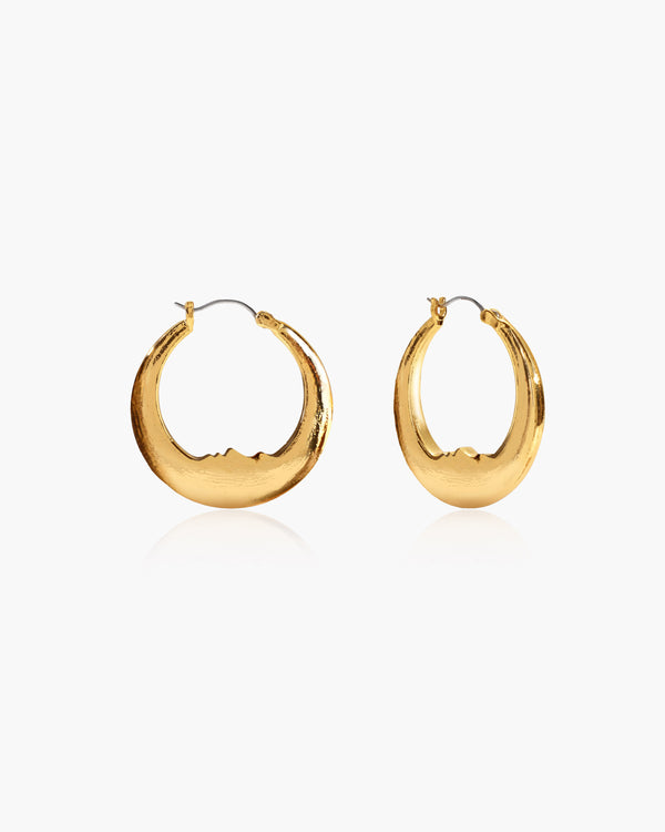 Gold Luna hoop earrings featuring a carved face on the inner curve, made of 18k gold plated brass.
