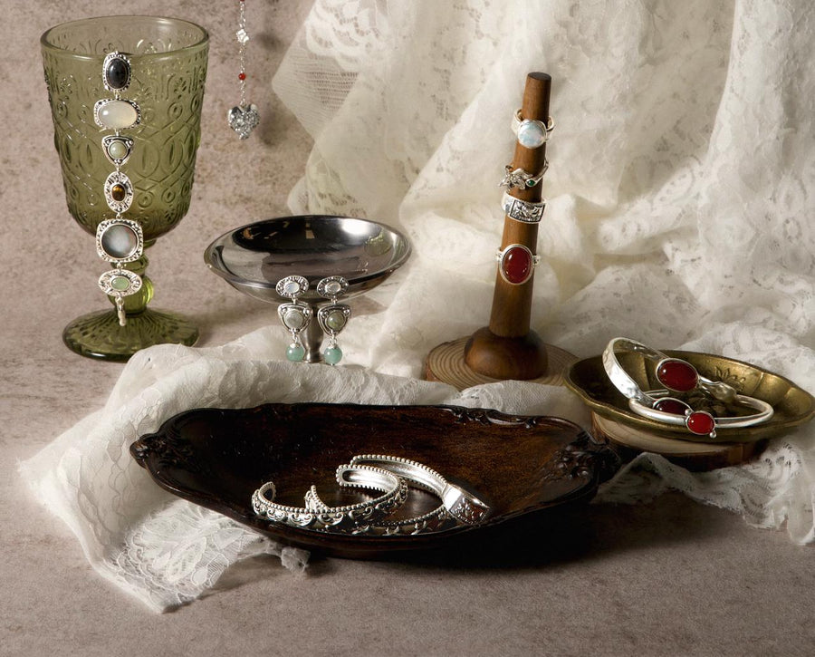 A vintage display of sterling silver rings, bangles, and gemstone earrings arranged to show different jewelry materials.
