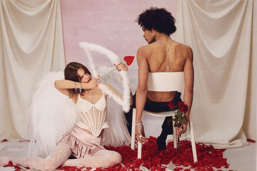 A couple posing with a cupid bow and red roses, featuring a long rosary necklace worn down the back for a romantic look.