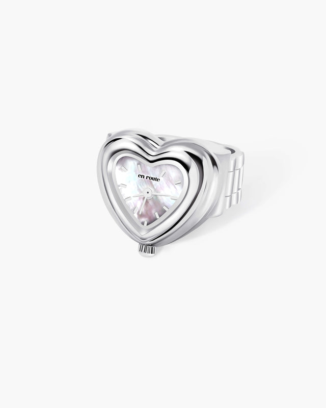 Silver heart watch ring with mother-of-pearl dial and 'en route' branding. Features watch-link band.